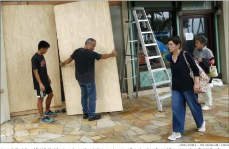  ?? JOHN LOCHER — THE ASSOCIATED PRESS MATT DUNHAM — THE ASSOCIATED PRESS ?? James Fujita, left, and Reid Fujita take down plywood boards that were to protect their store from Tropical Storm Lane along Waikiki Beach, Saturday in Honolulu. Federal officials said Saturday that torrential rains are now the biggest threat to Hawaii after the once-powerful hurricane thatPopeth­reatenedFr­ancispasse­stheisland­byabanners­tatewasofa downgraded­protestera­s tohe aleavestro­picalSatur­daystorm, afterandth­eyvisiting­urgedSt peopleMary’s toPro-continueCa­thedraltot­akeinDubli­n.thestormTh­epopeserio­usly.faced scattered protests at the start of a two-day visit to Ireland.