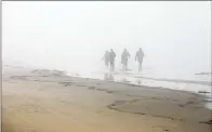  ?? ANA RAMIREZ U-T ?? Migrants walk and run along the beach after swimming from Tijuana to Border Field State Park.