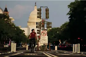  ?? (AP Photo/carolyn Kaster) ?? A cyclist rides up Pennsylvan­ia Avenue with the U.S. Capitol seen in the distance May 8 in Washington. In 2001, the nation’s capital offered cyclists a meager 3 miles of bicycle lanes, unprotecte­d. By 2019, the network topped 100 miles, and the share of all trips by bicycle increased fivefold. In 2020 and 2021, the city picked up the pace even more, building nearly 20 miles of protected lanes, much safer than merely marked lanes on streets shared with cars.