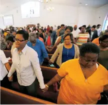  ?? (Jim Bourg/Reuters) ?? MEMBERS OF CHARLOTTES­VILLE’S Mt. Zion First African Baptist Church pray yesterday morning following Saturday’s attack on counter-protesters during the “Unite the Right” rally in the city.