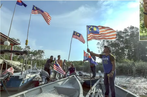  ?? — Bernama photo ?? Orang Asli in Kampung Baru, Kuala Benut place Jalur Gemilang flags on their boats.