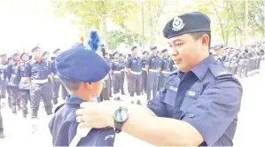  ??  ?? HARIS memakaikan lencana kenaikan pangkat kepada salah seorang kadet polis yang menyertai Perkemahan Kor Kadet Polis 2019 Peringkat Daerah Penampang.