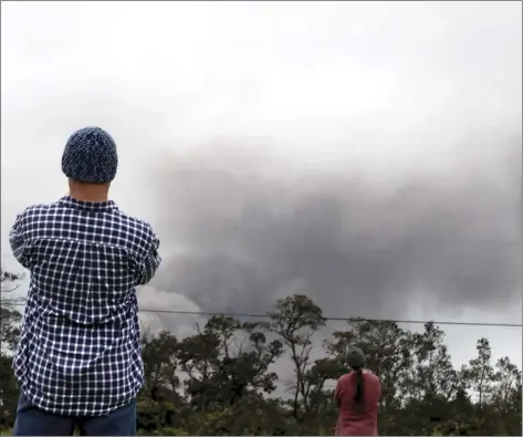  ?? AP photo ?? Joe Laceby, 47, of Volcano, Hawaii, watches as ash rises from the summit crater of Kilauea Volcano on Thursday. Laceby said he has sealed up his home and has gas masks to protect himself from the volcanic gases ash that is falling in the area.