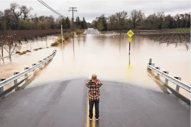  ?? Paul Kuroda / Special to The Chronicle 2019 ?? Colin Steen takes a photo of flooded Slusser Road after he crossed it with his heavy diesel pickup in Guernevill­e in 2019.