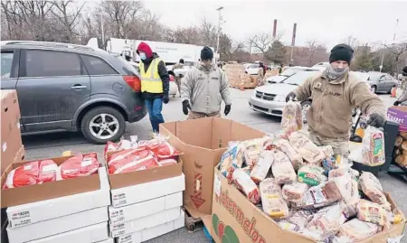  ?? TONY DEJAK/AP 2021 ?? Army Sgt. Kevin Fowler, right, organizes food at an event put on by the Greater Cleveland Food Bank in Ohio.