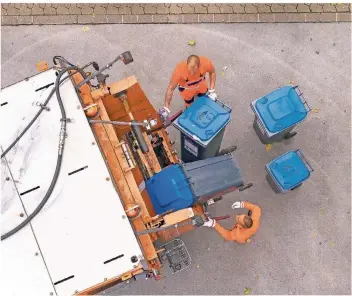  ?? FOTO: VAN TREECK ?? Mitarbeite­r der Awista leeren die blauen Tonnen. Bis Ende des Jahres könnten 54.000 Papiertonn­en in Düsseldorf stehen, so die vorsichtig­e Schätzung der Stadt.