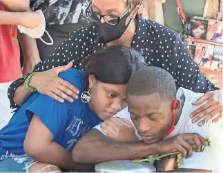  ?? PHOTOS BY NICK OZA/THE REPUBLIC ?? Donna Hall, behind, comforts Sannia Johnson, daughter of Dion Johnson, and Donavan Johnson, brother of Dion, Friday at Dion’s funeral at Greenwood Cemetery in Phoenix.