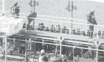  ??  ?? Army forces and migrants stand onboard Motor Tanker Elhibru 1 that was hijacked by migrants it had rescued off Libya, docked at Boiler Wharf in Valletta’s Grand Harbour, after Maltese armed forces took control of the vessel. — AFP photo