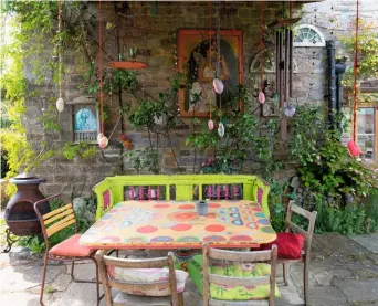  ??  ?? Layered flame orange ranunculus petals tinged with red planted in the trough by the barn (far left). The exotic rainbow-painted outdoor dining area inspired by Penny’s travels in India (left).