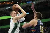  ?? TONY GUTIERREZ — THE ASSOCIATED PRESS ?? Dallas Mavericks center Kristaps Porzingis, left, takes a shot over Denver Nuggets center Nikola Jokic (15) in the first half Monday in Dallas.