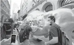  ?? ANDRE PENNER/AP ?? Activists paste the Portuguese word “hungry” on the Golden Bull on Nov. 17 outside the Brazilian B3 Stock Exchange in Sao Paulo, Brazil.