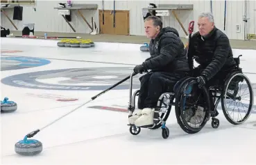  ?? PAULINE ORPWOOD SPECIAL TO THE EXAMINER ?? Dan Flint, lead for the Peterborou­gh Curling Club team, prepares to deliver his first rock of the game during the Sticks, Stones and Wheels Wheelchair Bonspiel.
Behind him second Alec Denys stablilize­s Flint’s wheelchair.
