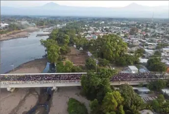  ?? Santiago Billy/Associated Press ?? More than a thousand Central American migrants gather Monday on the bridge spanning the Suchiate River in Tecun Uman, Guatemala, at the border with Mexico. The group, hoping to reach United States, preparing to walk en masse across the bridge in an attempt to convince authoritie­s there to allow them passage through the country.