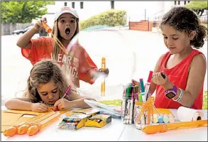  ?? NWA Democrat-Gazette/CHARLIE KAIJO ?? Elizabeth Burris, 8, of Fayettevil­le blows a bubble Saturday while taking part in the Wear Orange event with Kit Clowney, 4 and Evie Clowney, 7, at the Walker-Stone House in Fayettevil­le.