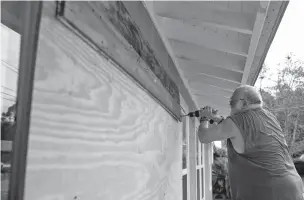  ?? JOSHUA BOUCHER/NEWS HERALD OF PANAMA CITY, FLA., VIA ASSOCIATED PRESS ?? David Hayes boards up a window at this home in Panama City, Fla., as Hurricane Michael approaches Tuesday. Panama City residents are among some 200,000 people ordered to evacuate ahead of the storm.