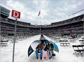  ?? FRED SQUILLANTE / COLUMBUS DISPATCH ?? The Humphreys from Jackson, Ohio, wait for Ohio State University’s spring commenceme­nt to begin Sunday. From left: father Charles, graduate Alexandrea (animal science major) and mother Tricia sit under umbrellas at Ohio Stadium.