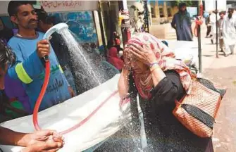  ?? AFP ?? Above: A volunteer showers a woman with water during a heatwave in Karachi on Tuesday. Left: Residents cool off during a hot summer day in Karachi on May 25.