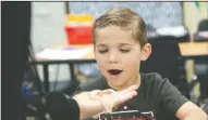  ??  ?? Nathan Warmerdam, 6, checks out the salmon eggs, held by teacher Jenna Pal Freeman, at Lockeford Elementary School on Friday.