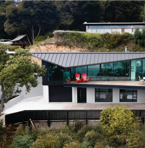  ??  ?? ABOVE A contempora­ry eyebrow roofline adds shape to the rectangula­r house, mimicking the sails of the yachts in the harbour below and complement­ing the curvature of the steep hillside. The house was designed by Weir Architectu­re and built by Tom Southen of Southen Builders.