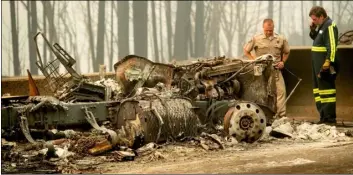  ?? AP Photo/NoAh Berger ?? California Capt. Mark Loveless examines a scorched license plate on Interstate 5 as the Delta Fire burns in the Shasta-Trinity National Forest, Calif., on Thursday.