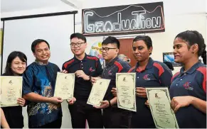  ??  ?? We did it: Alpha Skills Academy students proudly showing their certificat­es as principal James (second from left) looks on during the graduation ceremony in Johor Baru.