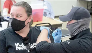  ?? (NWA Democrat-Gazette/Keith Bryant) ?? Liz Srader (left) receives her covid-19 vaccine, injected by firefighte­r engineer Chaz Harmon at a clinic the Bella Vista Fire Department hosted last week, at which firefighte­rs inoculated more than 1,300 people.