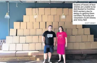  ?? Scott dewey ?? Dozens of boxes of face shields are unable to be distribute­d to frontline NHS workers due to delays in getting them certified. Pictured are volunteers Scott Dewey and Vicky Neil