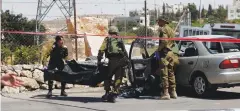  ?? (Mussa Qawasma/Reuters) ?? SOLDIERS CARRY the body of a Palestinia­n assailant from the scene of a carramming attack at the entrance to Beit Anun village near Hebron on the West Bank.