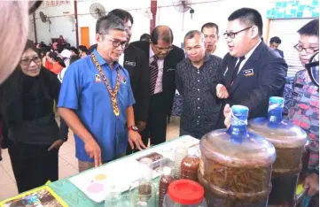  ??  ?? Dr Annuar (left) and others are being briefed by a student at the exhibition.