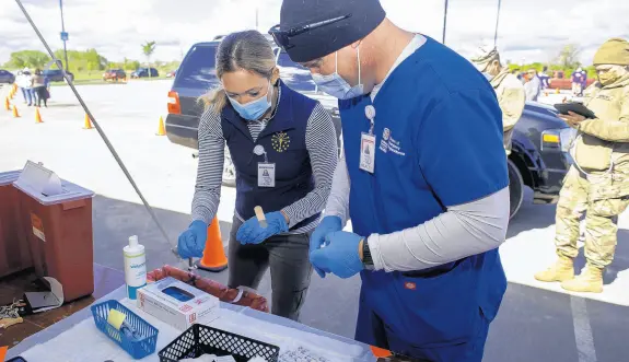  ?? MICHAEL GARD/POST-TRIBUNE PHOTOS ?? Dr. Lindsay Weaver, left, chief medical officer at the Indiana State Department of Health, and vaccinator Joseph Kalocinski prepare vaccine shots at Wolf Lake Pavilion in Hammond on Saturday.