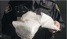  ?? CHRIS YOUNG/THE CANADIAN PRESS ?? An Ontario Provincial Police officer displays bags containing fentanyl during a news conference in Vaughan, Ont., in February. The RCMP has launched at least 20 investigat­ions involving dozens of vendors shipping fentanyl from China.