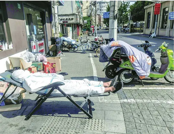  ?? EFE ?? Un repartidor de comida a domicilio descansa en plena calle en Shanghai