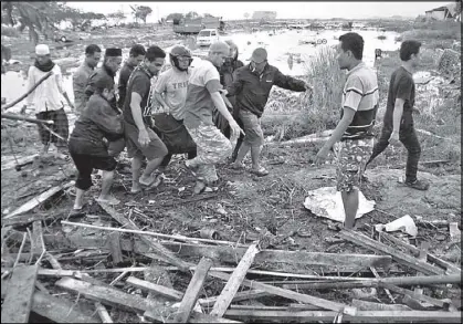  ?? AP ?? Residents carry a body bag of a tsunami victim yesterday in Palu, Central Sulawesi, Indonesia.