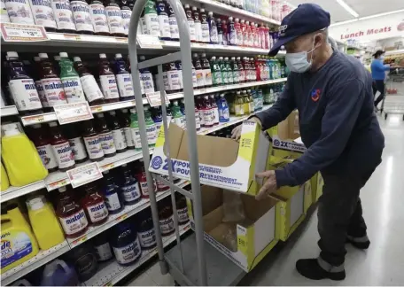  ?? AP PHOTOS ?? STOCKING UP: A worker stocks shelves Wednesday at the Presidente Supermarke­t in Miami’s Little Havana while, in Chicago, signs at a Target store show that retailers are hiring again.