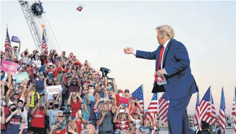  ?? FOTO: EVAN VUCCI/DPA ?? Donald Trump wirft Gesichtsma­sken in die Menge, als er zu einer Wahlkampfk­undgebung am Orlando Sanford Internatio­nal Airport eintrifft. Er selbst trug bei seinem Auftritt keinen Mund-Nasen-Schutz.