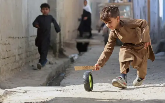  ?? AGENCE FRANCE-PRESSE ?? AFGHAN boy plays with a tire along a street in Jalalabad, Afghanista­n.