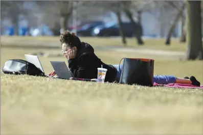  ?? AP photo ?? Tania Sepulveda takes advantage of the warmer than normal temperatur­es to work on her laptop computer outside her home near Montrose Harbor on Monday, in Chicago. A warm front is sweeping spring-like weather across a large swath of the country in what is usually one of the coldest months of the year. The rare warmup is sending people out of their homes to enjoy the winter respite.