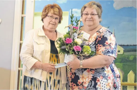  ?? KATHY JOHNSON PHOTOS ?? Roseway Manor Administra­tor Cathy Hambleton, right, presents a flower arrangemen­t and card of thanks to Barb Henderson, president of the Roseway Hospital Auxiliary, for the auxiliary’s recent contributi­on to the manor of a blanket and towel warmer and new lounge furniture.