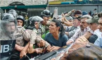  ?? — AFP ?? Opposition activists scuffle with riot police during a protest against the government in Caracas on Friday.