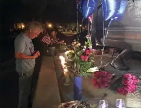  ?? THE ASSOCIATED PRESS ?? A man lights candles at a memorial for two slain police officers in Palm Springs, Calif., on Saturday.