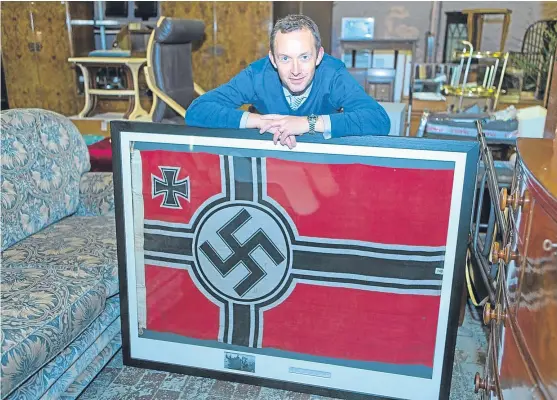  ?? Picture: Steven Brown. ?? Auction house proprietor Steven Dewar with the Nazi flag from U-boat 2326, which surrendere­d in Dundee in 1945.
