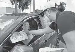  ?? MATIAS J. OCNER/ MIAMI HERALD VIA TNS ?? Tatiana Fernandez, 49, a city employee, distribute­s printed unemployme­nt forms to Miami- Dade County residents in Hialeah, Fla., on April 7.