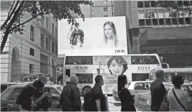  ?? VINCENT YU/AP PHOTO ?? People walk past a fashion advertisem­ent in Hong Kong on April 5.