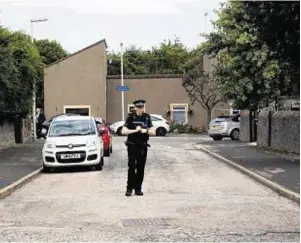  ??  ?? A police officer stands guard in the street ahead of the cordon