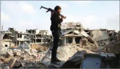  ?? MOHAMAD ABAZEED/AFP ?? A rebel fighter stands amid destroyed buildings in the rebel-held area of Daraa, in southern Syria, on March 14.