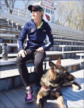  ?? Tyler Sizemore / Hearst Connecticu­t Media ?? Amy Dixon, a blind tri-athlete, talks beside her guide dog, Woodstock, after running warm up laps on the track at Greenwich High School in 2016.