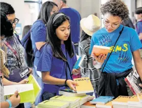  ?? Melissa Phillip / Staff file photo ?? Mia Proo, left, and Ryenn Spiller, both sixth-graders at West Briar Middle School in Houston ISD, look at books during the Tweens Read Book Festival.