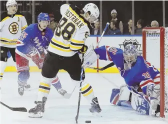  ?? AP PHOTO ?? TRICKY STICK: David Pastrnak reaches back for the puck before putting it past Rangers goalie Henrik Lundqvist in the first period of last night’s game.