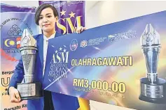  ??  ?? Jun Hoong showing the trophy and replica cheque after she was crowned 2017 Malaysian Universiti­es Sports Council (Masum) Sportswoma­n. — Bernama photo