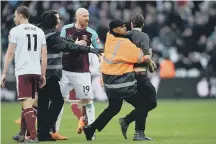  ??  ?? A West Ham steward tackles a pitch invader at the London Stadium.